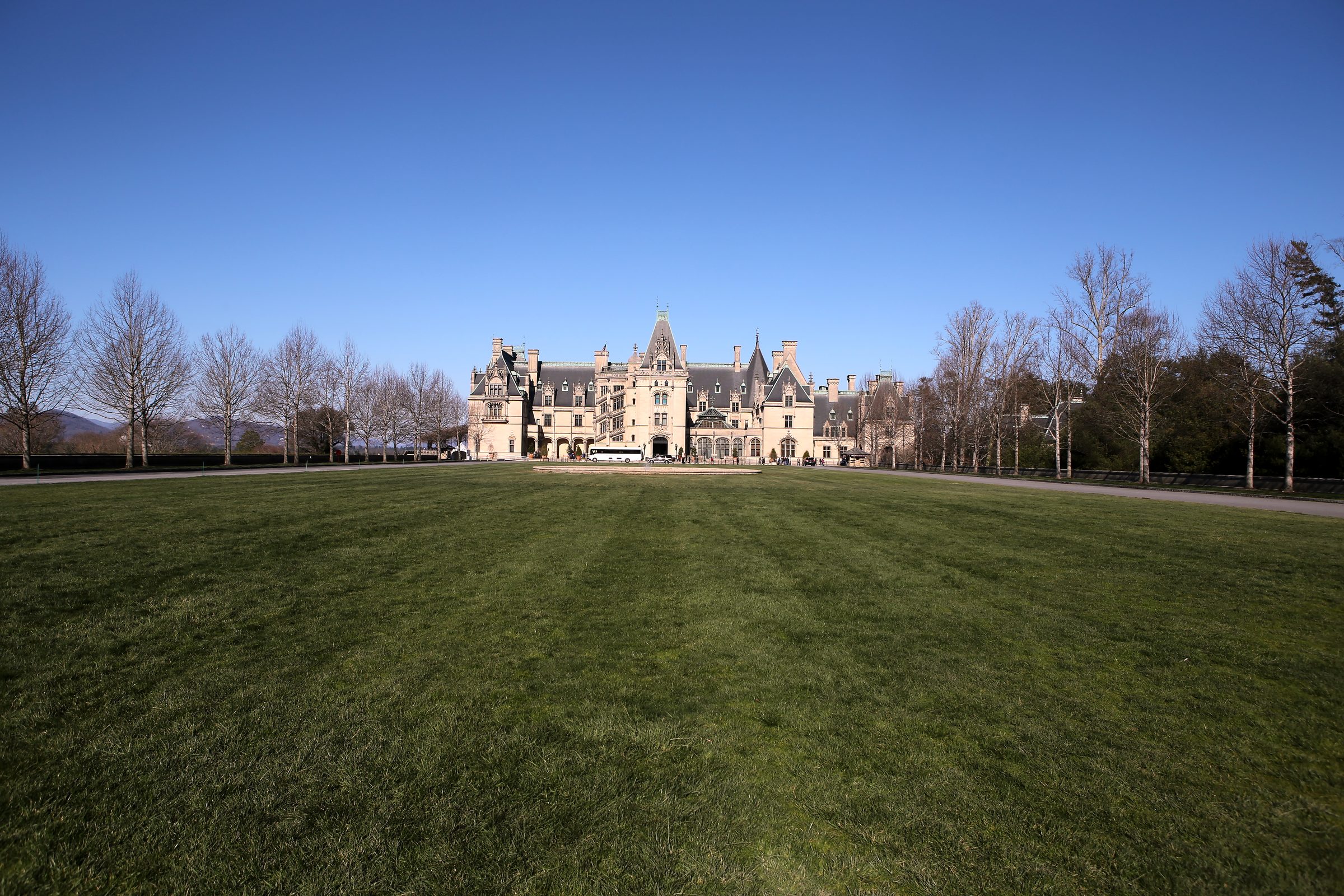 Grand stone chateau across a wide flat green lawn.