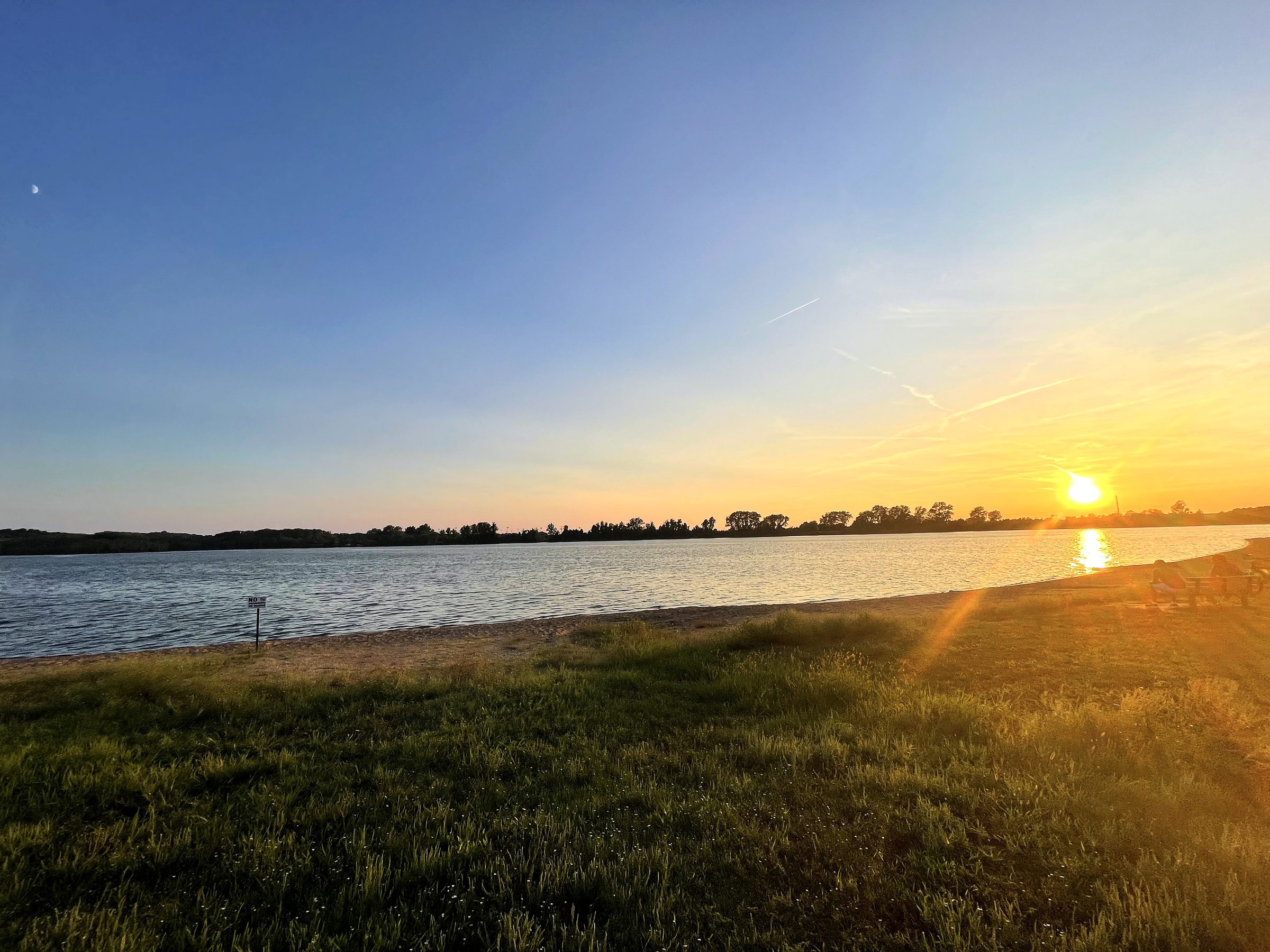 Golden-hour shoreline and flat water at soft sundown.