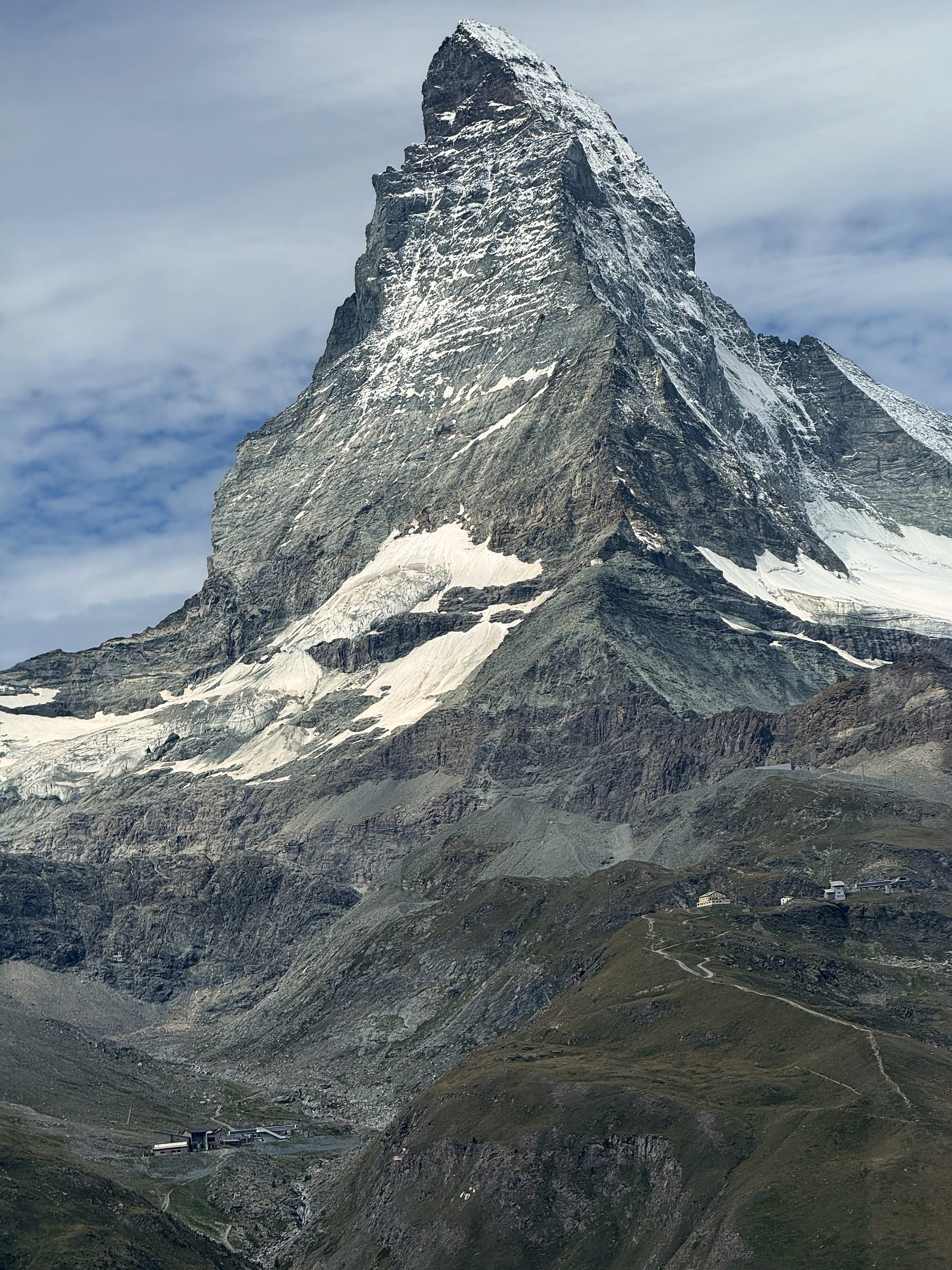 Trail snaking through alpine terrain toward the Matterhorn pyramid.