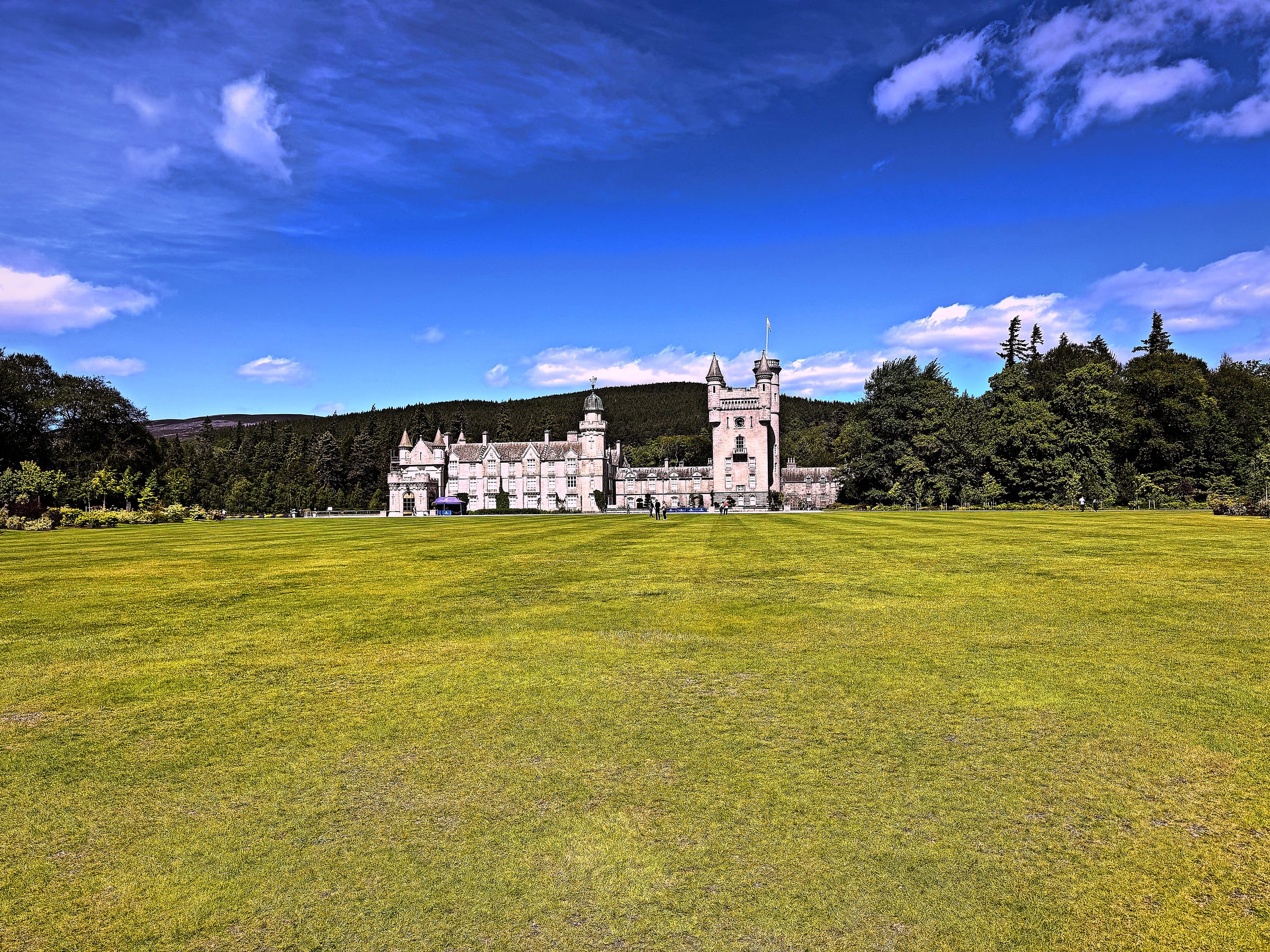 Long royal lawn aiming at white turrets of Balmoral Castle.