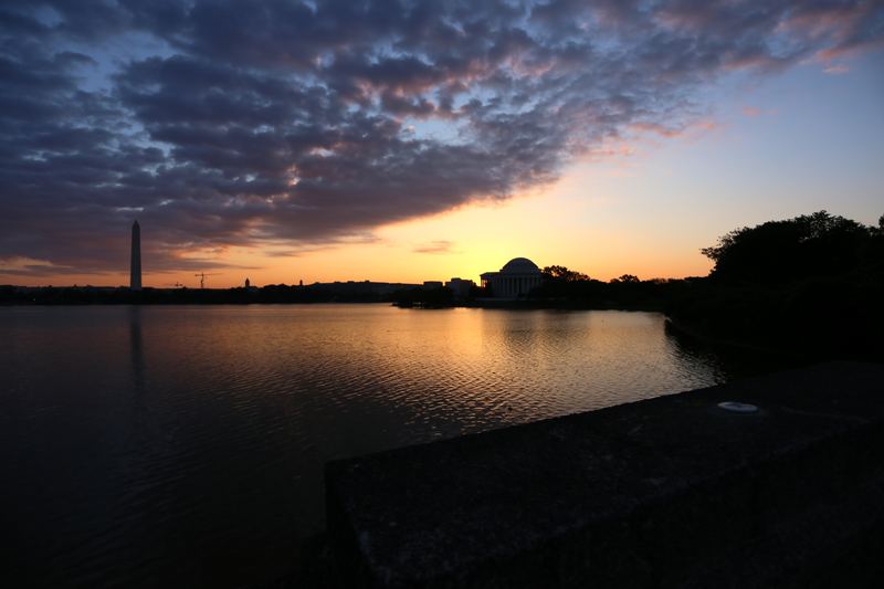 Washington Monument and memorial silhouettes against gold basin sunset.