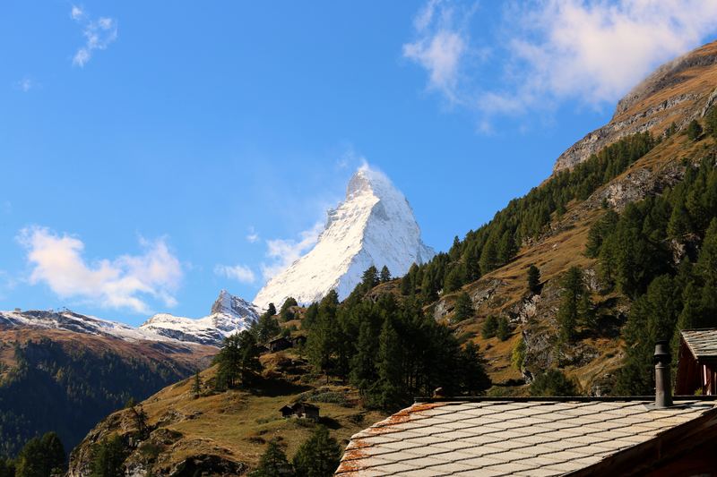 Matterhorn above green alpine slope with stone-shingle roof edge.