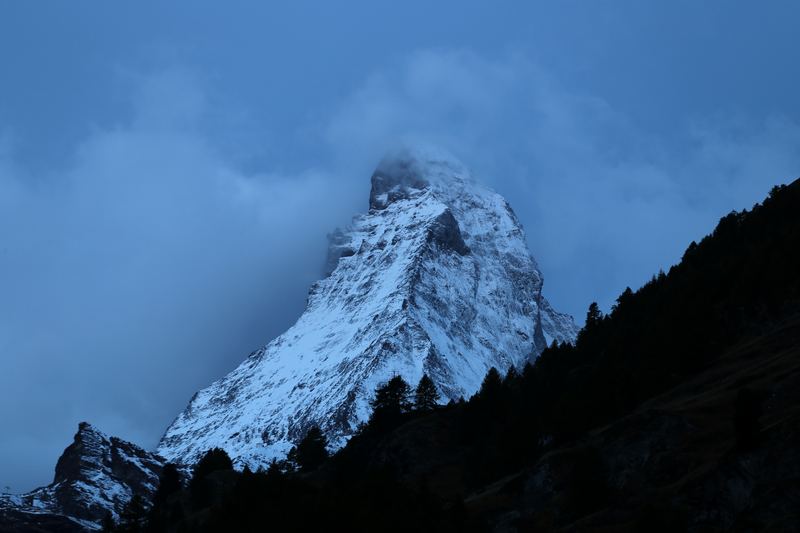 Blue-hour Matterhorn half-swallowed by thick mist.