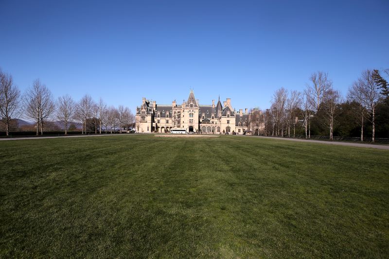 Grand stone chateau across a wide flat green lawn.