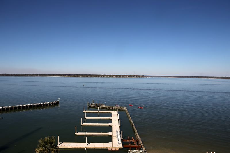 High wooden pier over calm blue bay under clear sky.