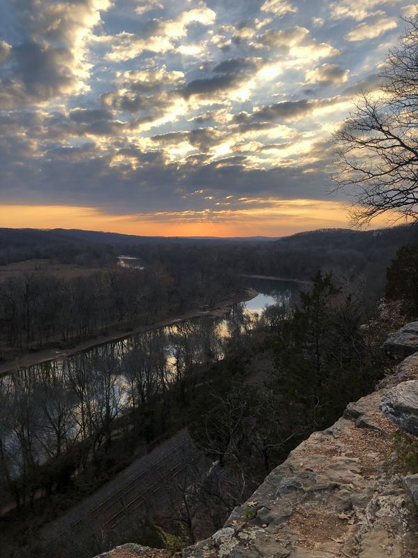 Overlook down to a river bend catching sunset on popcorn clouds.