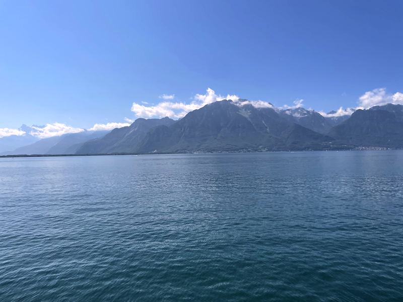 Open teal lake fetching toward distant clouded mountain peaks.