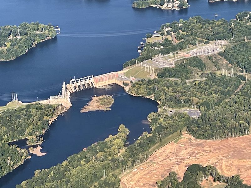 Aerial dam and reservoir branching through green forest.
