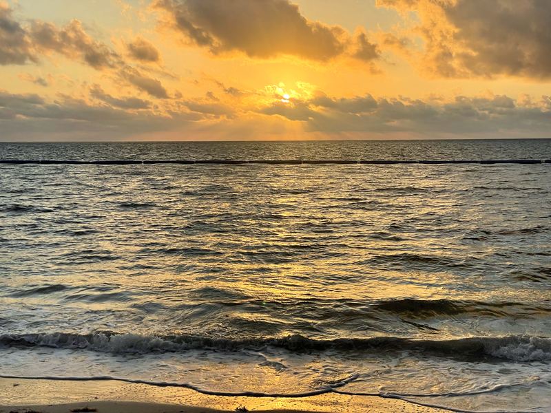 Choppy waves under golden rays filtering through thick cloud.