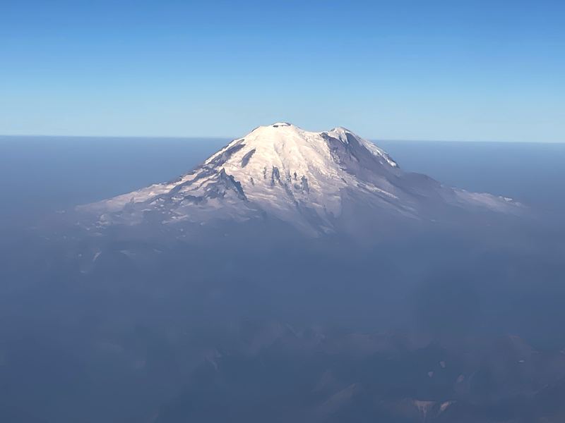 Isolated snow volcano peak floating in clear blue air.