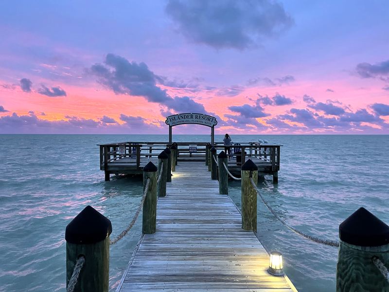 Wooden pier into turquoise water under pink-purple afterglow.