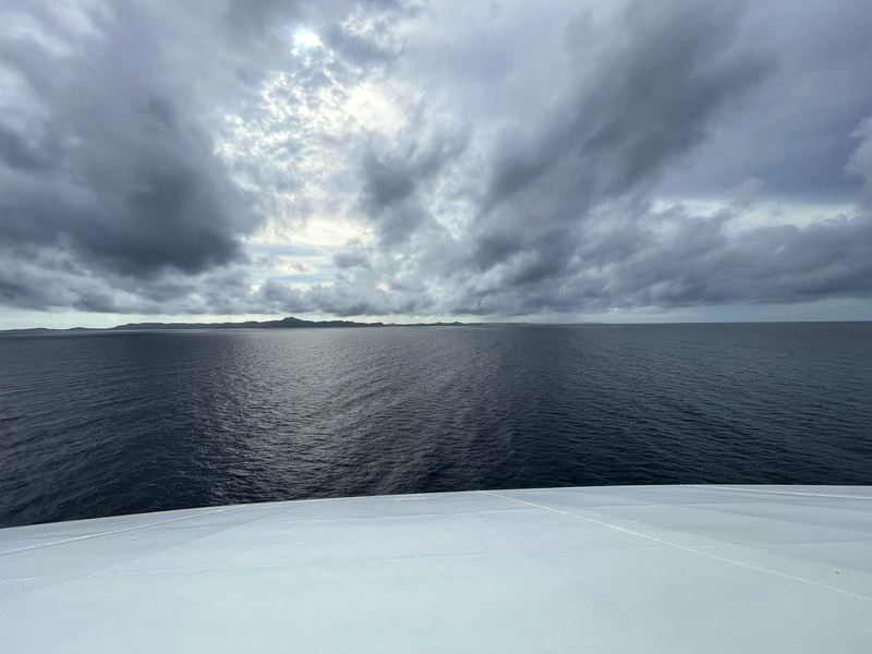 Curving deck view toward a dark stormy open coast.