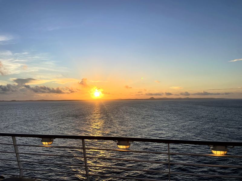 Ship-deck lamps above a gold sun path on the ocean.