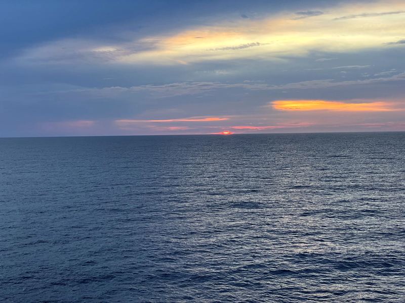 Vast dark blue sea with a thin ember of light on the horizon.