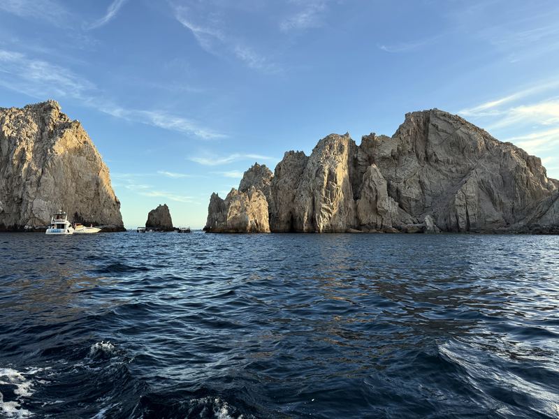 Yacht near towering tan cliffs at Cabo's land's end.